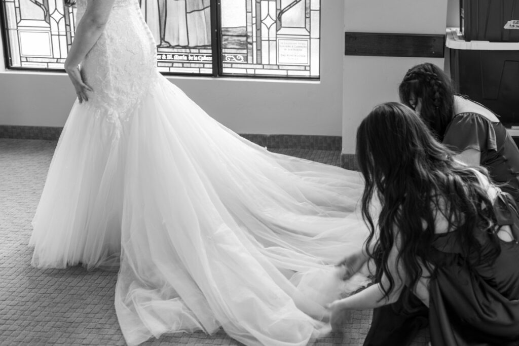 Bridesmaids adjust the Catholic Bride's train in the Bride's Room before the California Catholic Wedding.