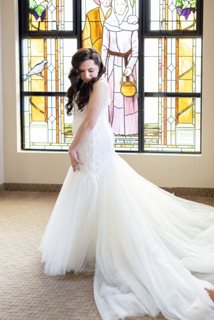 Catholic Bride watches as her train is being adjusted before the California Catholic Wedding.