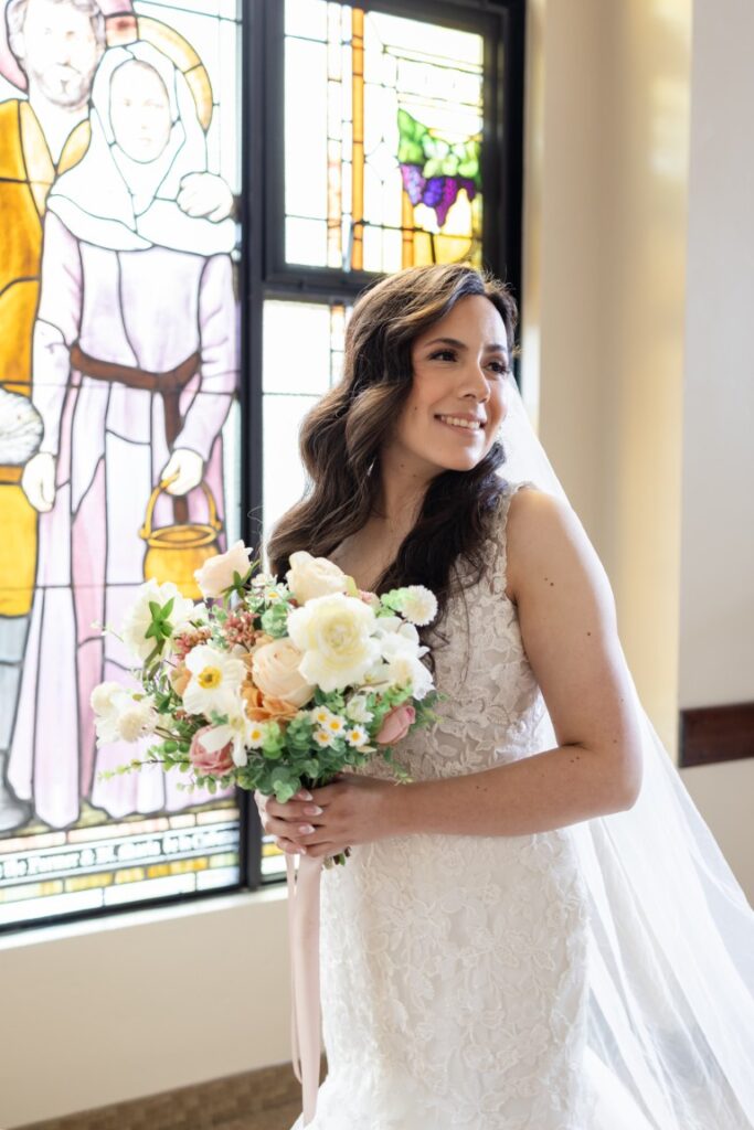 Catholic bride smiles with a bouquet of flowers before the California Catholic Wedding.