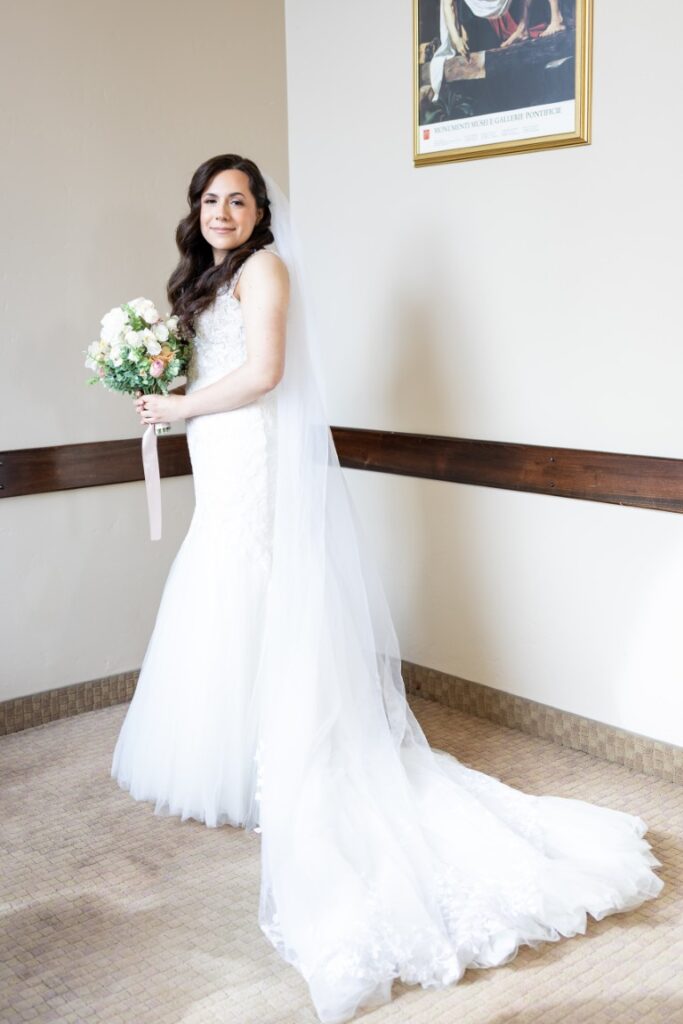 Catholic bride smiles with a bouquet of flowers before the California Catholic Wedding.