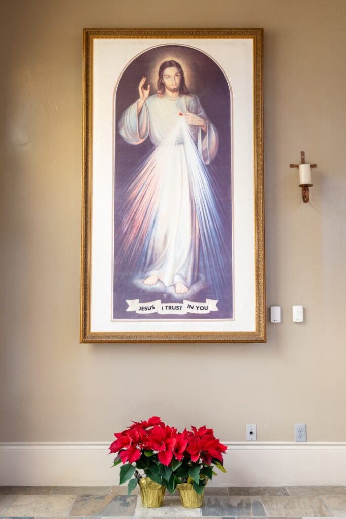 Divine Mercy image of Jesus with poinsettias beneath it before the California Catholic Wedding.