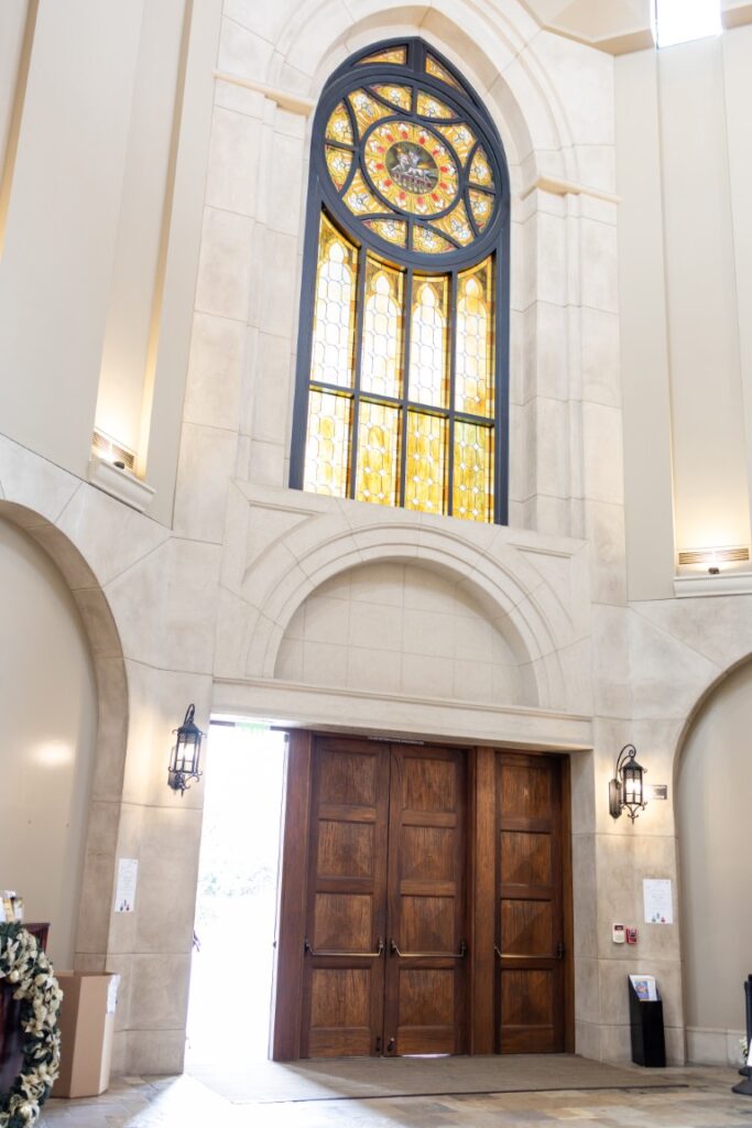 St. Stanislaus Church stained glass window and door is propped open before the California Catholic Wedding.