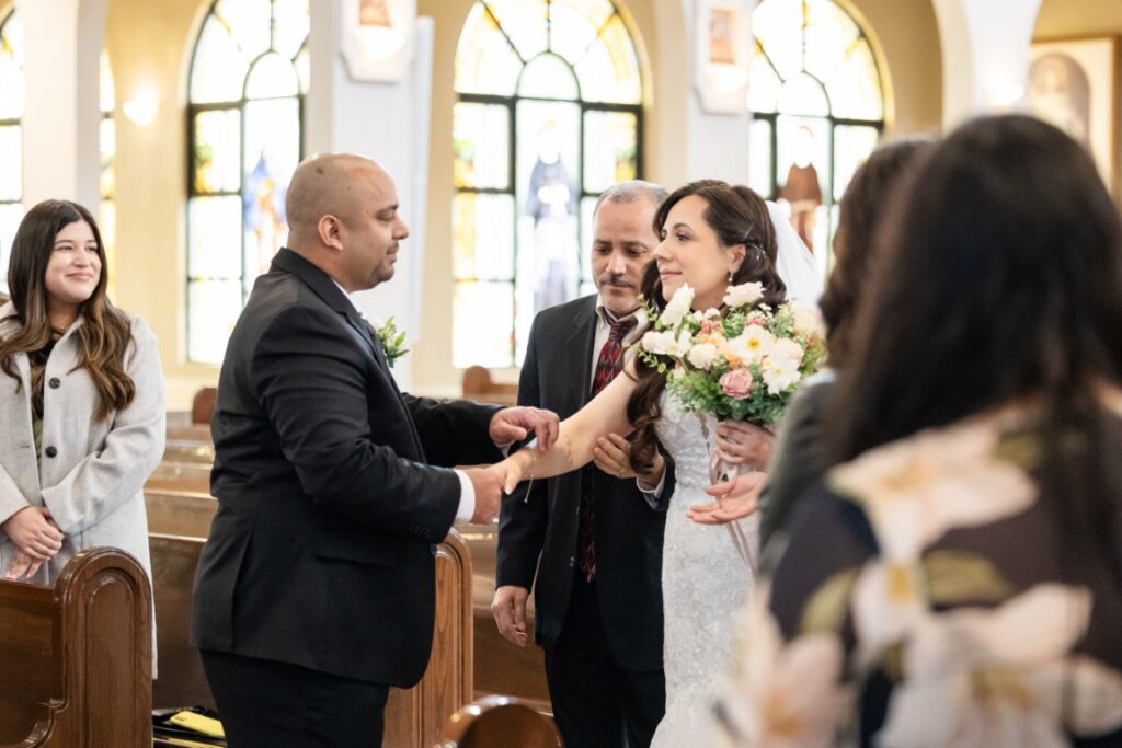Catholic bride and groom join hands at the altar.