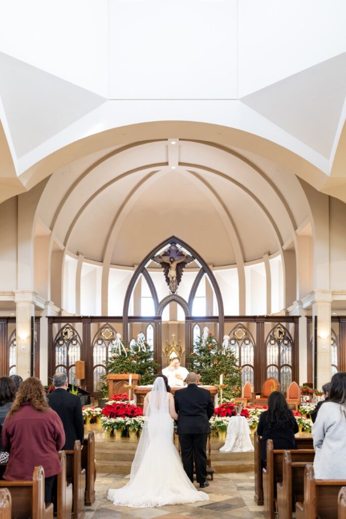 View of bride and groom at the altar with the priest beginning Mass
