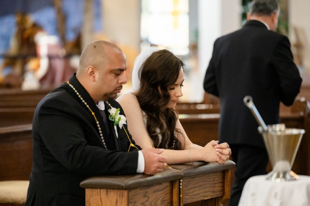 Catholic bride and groom praying after receiving the Eucharist.